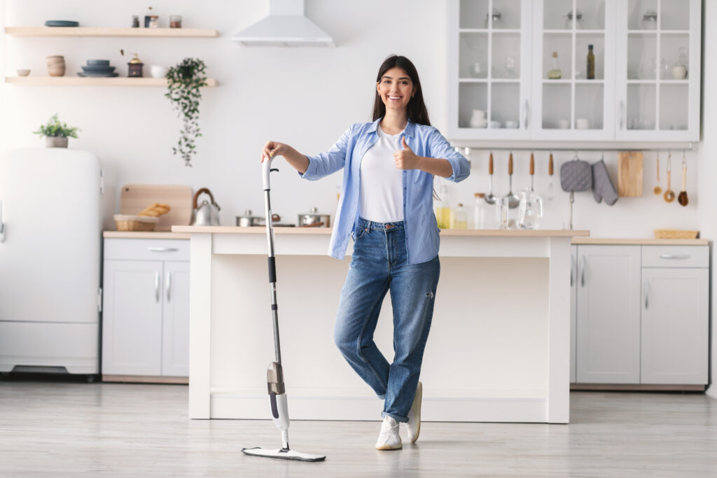 Femme debout souriante dans sa cuisine 